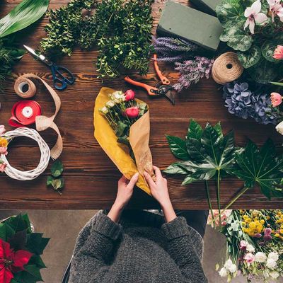 Zugeschnittenes Bild des Blumenhändlers, der Blumenstrauß in gelbes Packpapier einwickelt